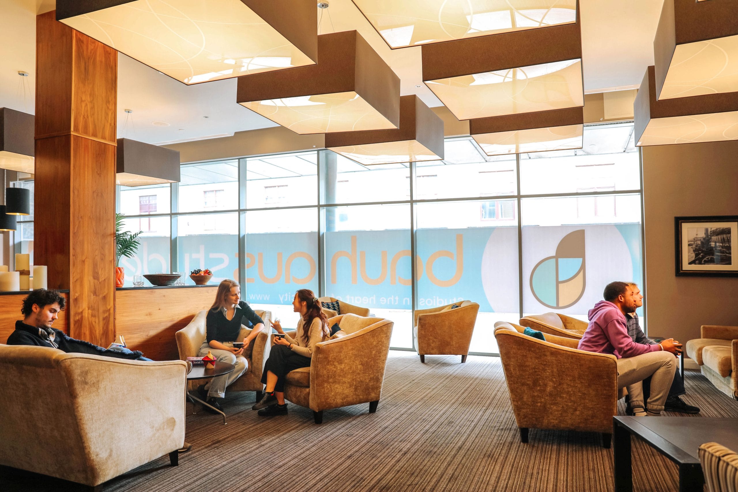 A group of students studying and socialising in the St Andrews Street Bauhaus student Accommodation Communal area